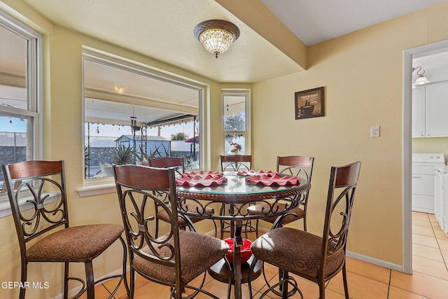 dining room featuring light tile patterned floors, washer / clothes dryer, and baseboards