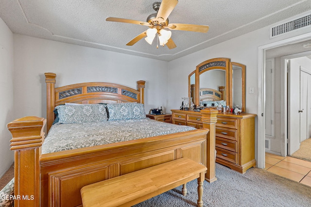 bedroom with light tile patterned floors, visible vents, light carpet, ceiling fan, and a textured ceiling