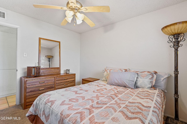 bedroom with carpet, visible vents, a ceiling fan, and a textured ceiling