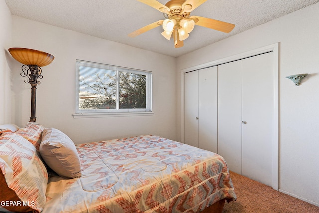 bedroom with a textured ceiling, ceiling fan, a closet, and carpet