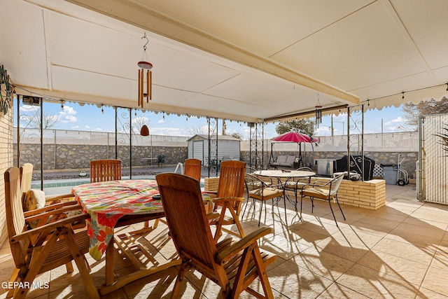 view of patio / terrace featuring a storage unit, outdoor dining space, and an outbuilding