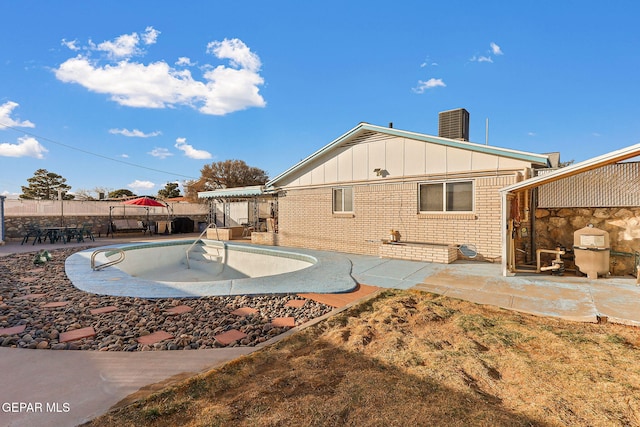 back of property featuring a fenced in pool, brick siding, board and batten siding, a patio area, and fence