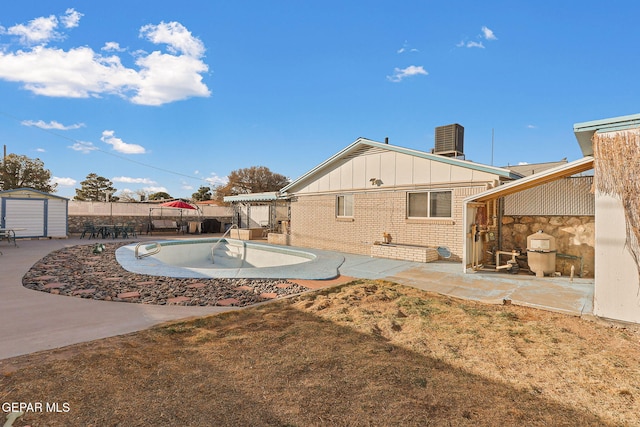 back of property with brick siding, board and batten siding, a patio area, a shed, and a fenced backyard