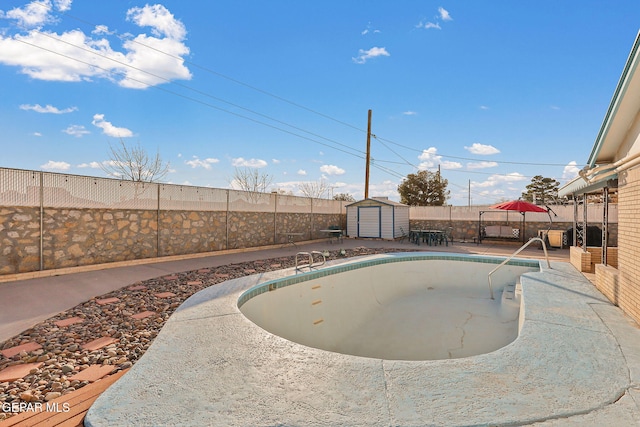 view of swimming pool featuring an outbuilding, a fenced backyard, a patio, and a shed