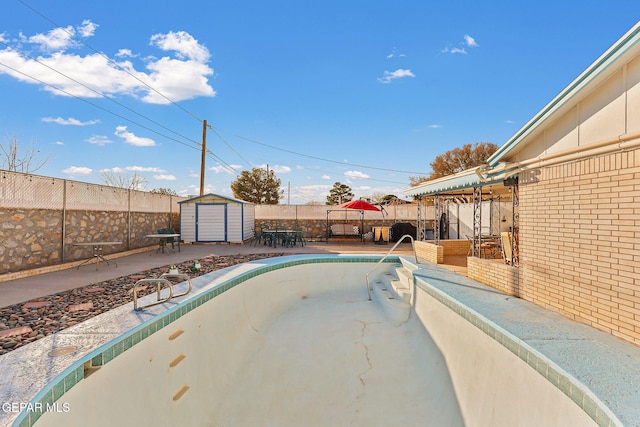 view of pool with an outbuilding, a fenced backyard, a patio, and a storage shed