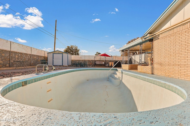 view of swimming pool featuring a fenced backyard, an outdoor structure, and a storage unit