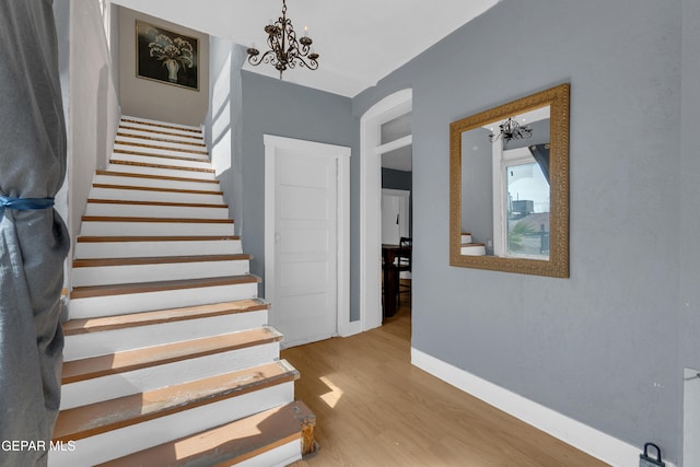 stairs with a chandelier, baseboards, and wood finished floors