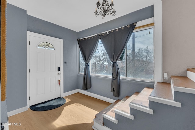 foyer entrance featuring an inviting chandelier, baseboards, stairway, and wood finished floors