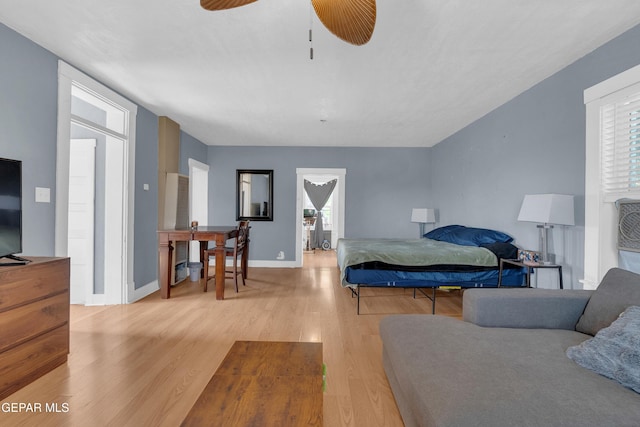 bedroom featuring ceiling fan, multiple windows, wood finished floors, and baseboards