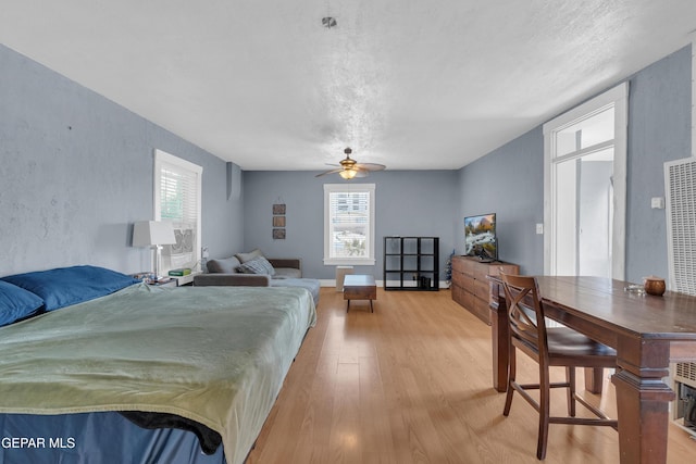 bedroom featuring light wood finished floors, multiple windows, and baseboards