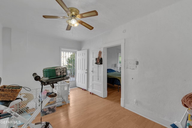 interior space featuring light wood-type flooring, a ceiling fan, and baseboards