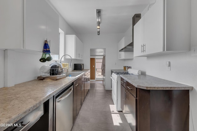 kitchen featuring a sink, white cabinetry, white range with gas cooktop, stainless steel dishwasher, and wall chimney range hood