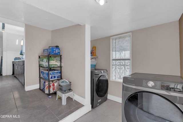 laundry area with laundry area, washer and clothes dryer, tile patterned floors, and baseboards