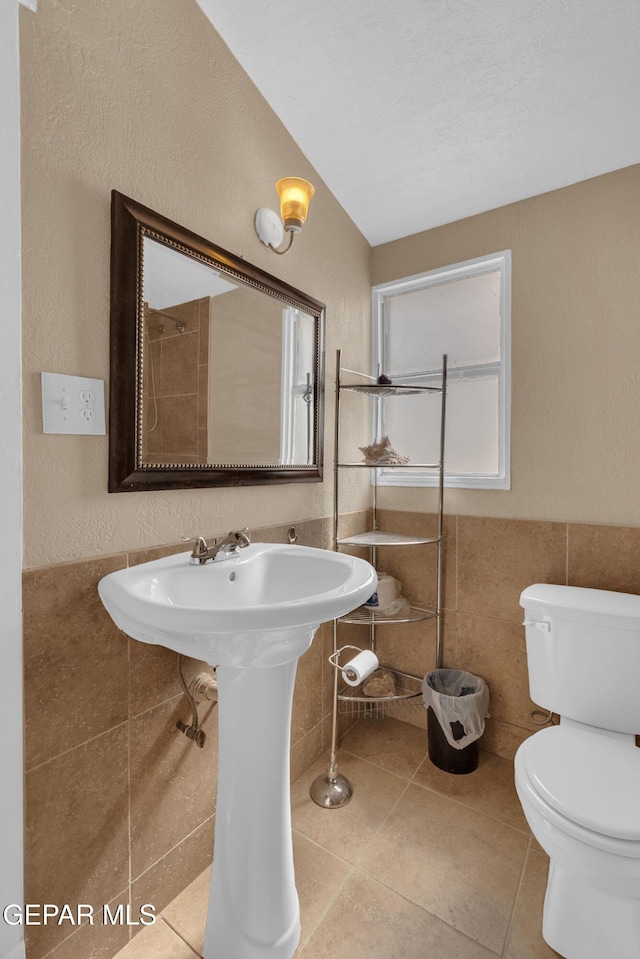 bathroom with tile patterned flooring, a wainscoted wall, tile walls, and toilet