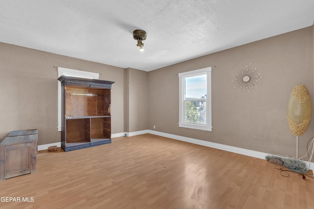 spare room with a textured ceiling, wood finished floors, and baseboards