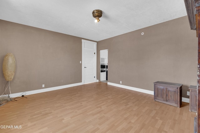 unfurnished room with light wood-style flooring and baseboards