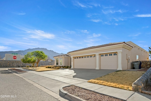 view of front of house with a tiled roof, a mountain view, concrete driveway, and stucco siding