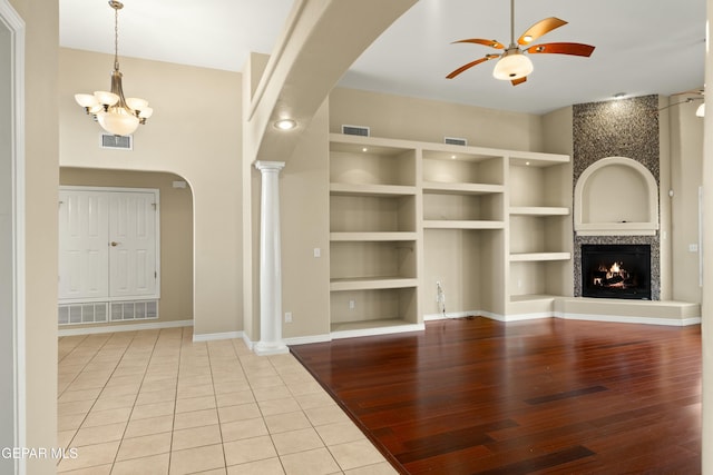 unfurnished living room with built in shelves, visible vents, and arched walkways