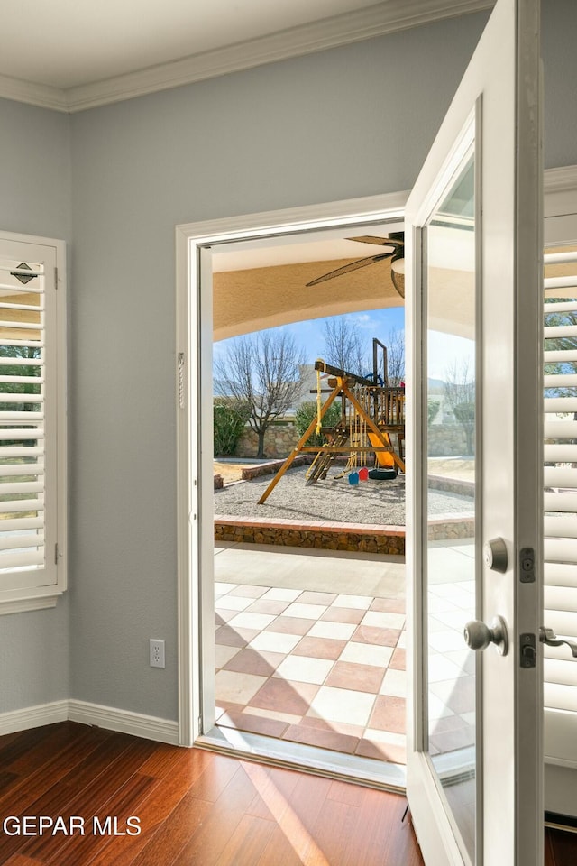 doorway to outside with dark wood-type flooring, crown molding, baseboards, and ceiling fan