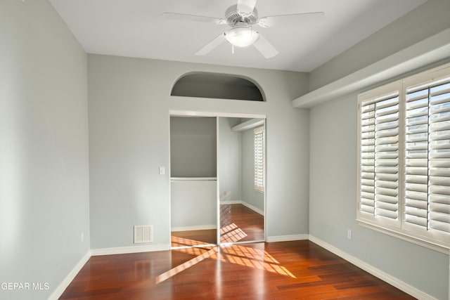 spare room featuring a ceiling fan, baseboards, visible vents, and wood finished floors