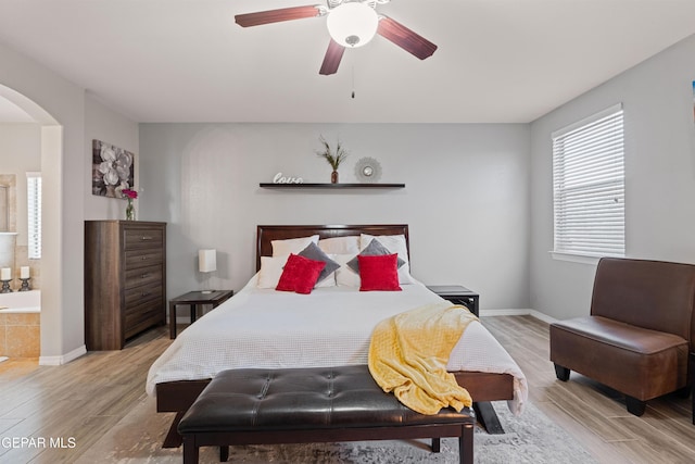 bedroom featuring baseboards, ceiling fan, arched walkways, and wood finished floors