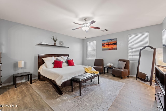 bedroom with light wood-style flooring, visible vents, baseboards, and ceiling fan