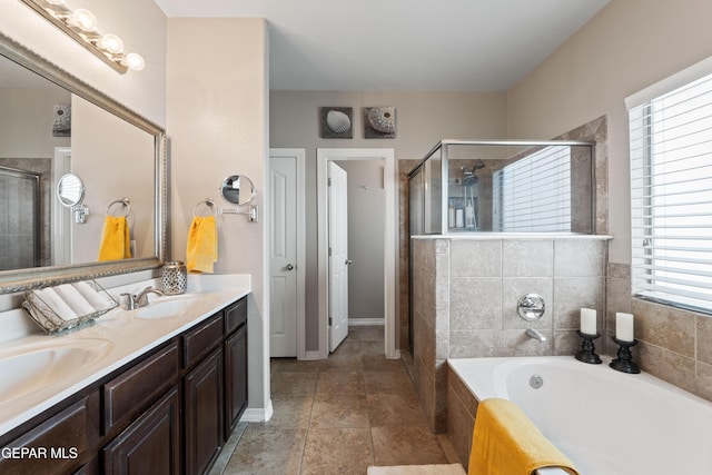 bathroom with double vanity, a stall shower, a garden tub, and a sink