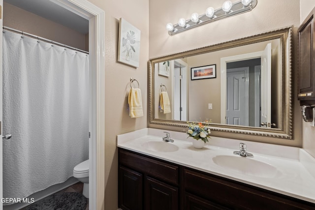 bathroom with a shower with curtain, a sink, toilet, and double vanity