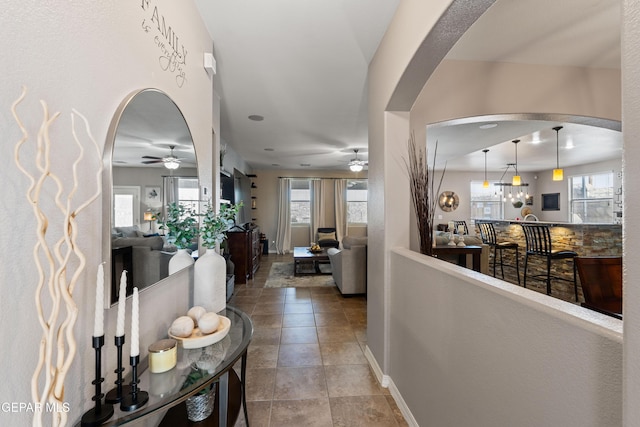 hall with arched walkways, plenty of natural light, and baseboards