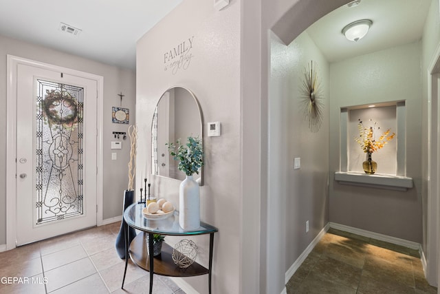 interior space featuring arched walkways, visible vents, and baseboards