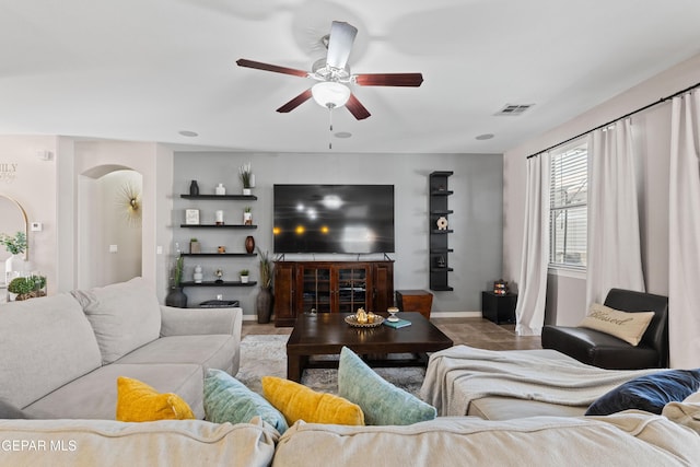 living room with a ceiling fan, visible vents, and baseboards