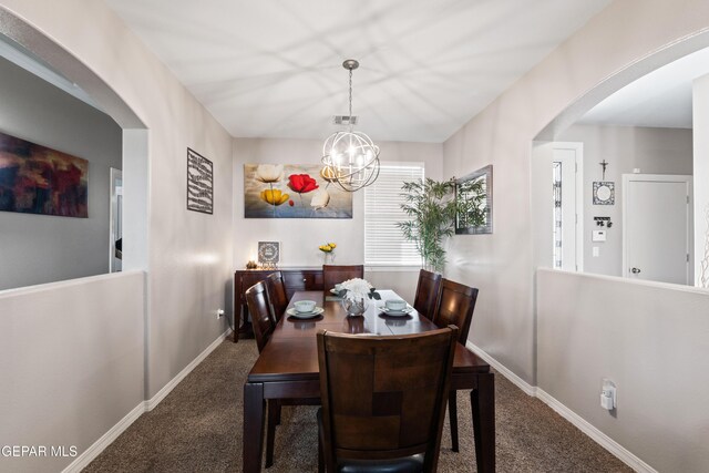 carpeted dining room featuring arched walkways, visible vents, baseboards, and an inviting chandelier