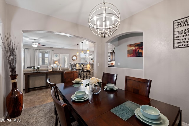 dining room with arched walkways and ceiling fan with notable chandelier