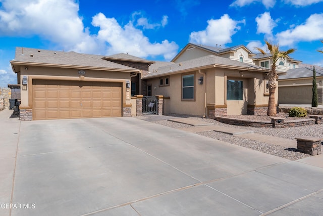 view of front of property with an attached garage, stone siding, concrete driveway, a gate, and stucco siding