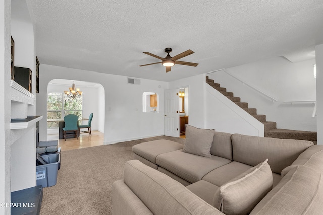 living area featuring arched walkways, visible vents, light carpet, a textured ceiling, and stairs