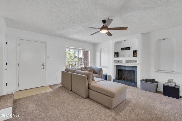 carpeted living area featuring a fireplace, a textured ceiling, and ceiling fan