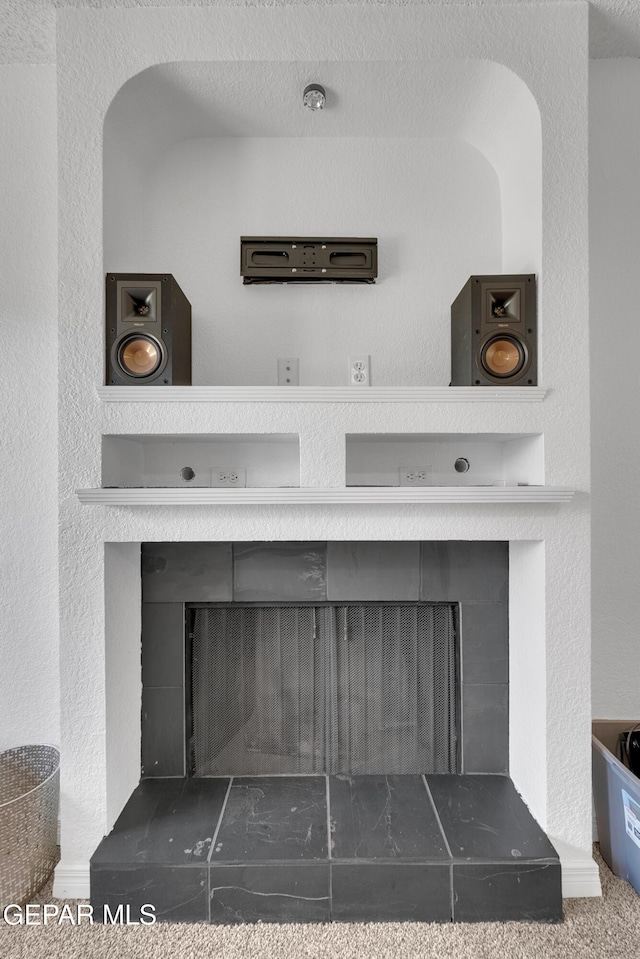 details featuring a textured wall and a tiled fireplace