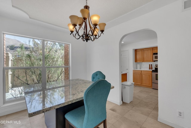 dining space featuring baseboards, visible vents, arched walkways, and a notable chandelier