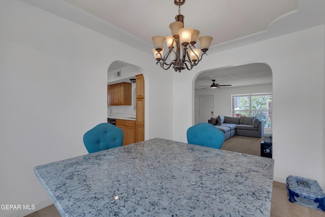 dining room with arched walkways, visible vents, baseboards, and ceiling fan with notable chandelier