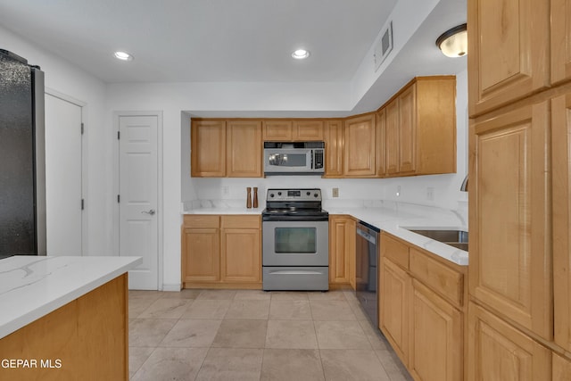 kitchen featuring appliances with stainless steel finishes, visible vents, a sink, and light stone countertops