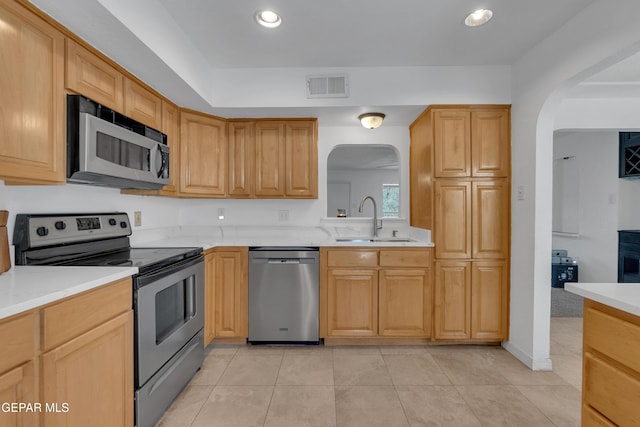 kitchen featuring arched walkways, visible vents, stainless steel appliances, light countertops, and a sink