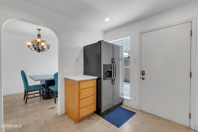 kitchen featuring a notable chandelier, stainless steel fridge, arched walkways, and a wealth of natural light