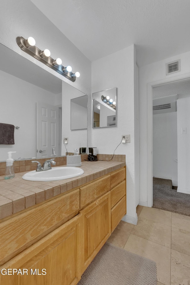 bathroom featuring tile patterned flooring, visible vents, vanity, and a textured ceiling