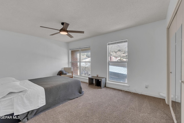 bedroom featuring a textured ceiling, a closet, carpet, and a ceiling fan