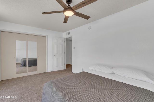 unfurnished bedroom with carpet floors, a closet, visible vents, a ceiling fan, and a textured ceiling