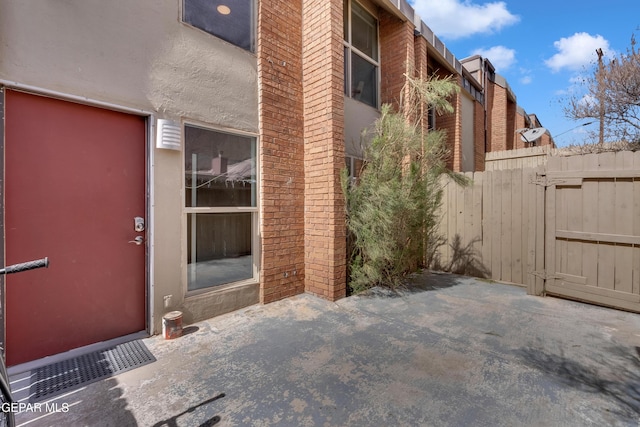 exterior space featuring a patio area, fence, brick siding, and stucco siding