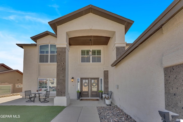 property entrance featuring a patio, french doors, and stucco siding