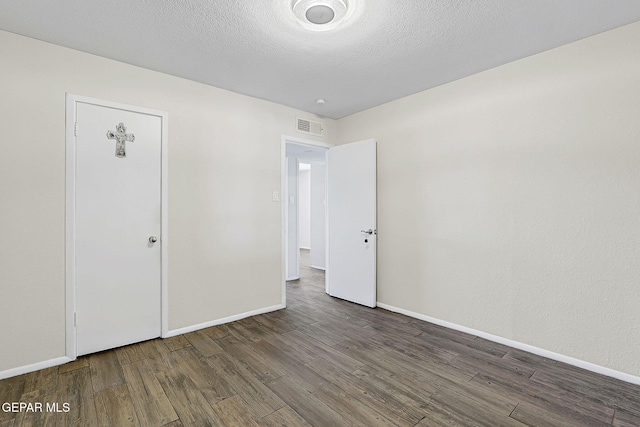 unfurnished bedroom with baseboards, a textured ceiling, visible vents, and wood finished floors