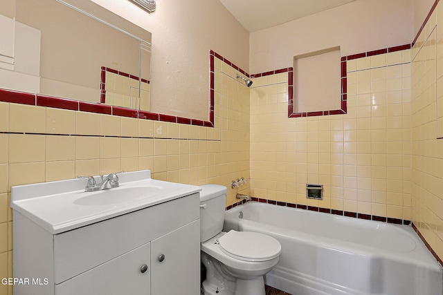 bathroom featuring toilet, shower / bathtub combination, vanity, and tile walls