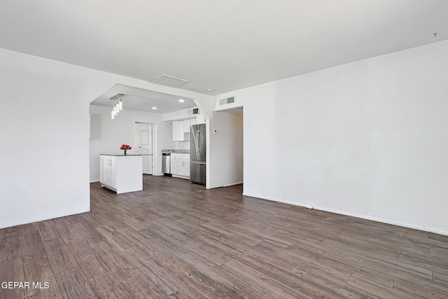 unfurnished living room with baseboards, visible vents, and dark wood-style flooring